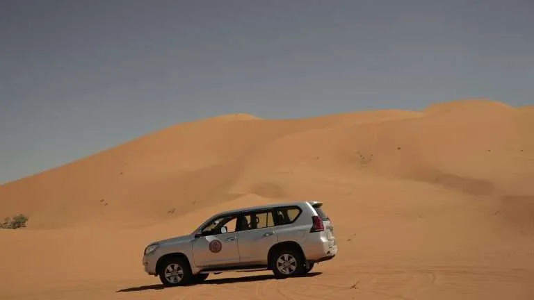 Toyota Prado with Saharaï logo on the side driving across the Erg Chebbi Dunes in Merzouga