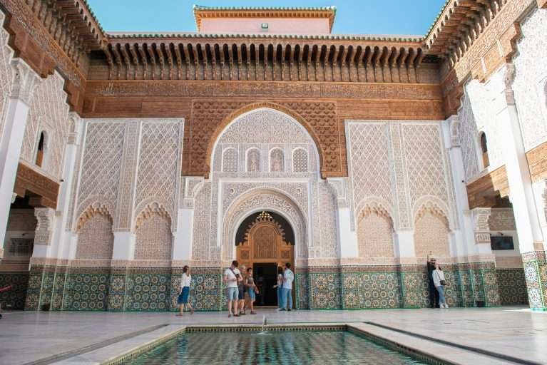 Ornate courtyard entrance with carved arches and zellige tilework in Marrakech at the Madrasa Ben Youssef