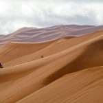 Wind-shaped Sahara sand dunes in Morocco with motorbikes coming down the Erg Chebbi dunes in Merzouga