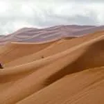 Wind-shaped Sahara sand dunes in Morocco with motorbikes coming down the Erg Chebbi dunes in Merzouga