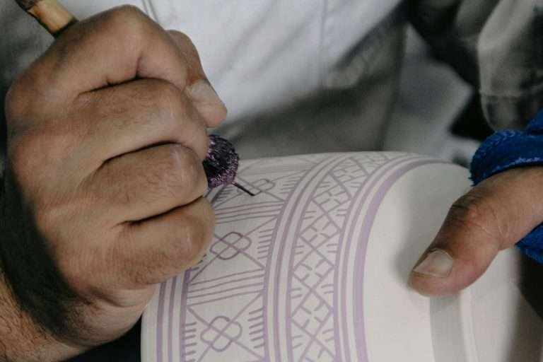 Artisan painting geometric patterns on Moroccan pottery in Fes