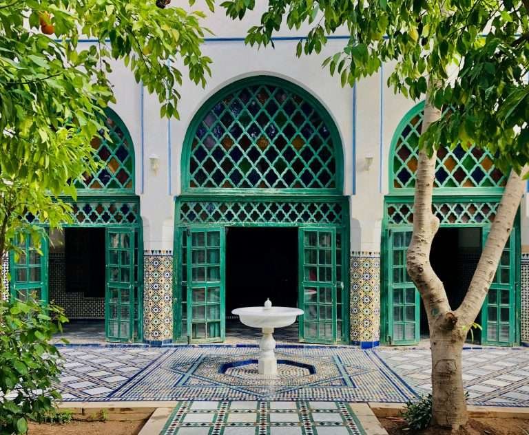 Green-tiled courtyard with arched doorway and central fountain in Marrakech at the Bahia Palace
