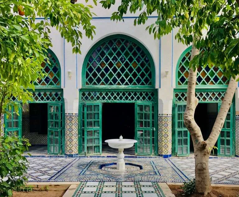 Green-tiled courtyard with arched doorway and central fountain in Marrakech at the Bahia Palace
