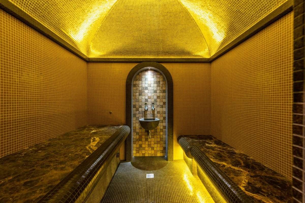 Golden-lit hammam spa room with mosaic walls in Morocco
