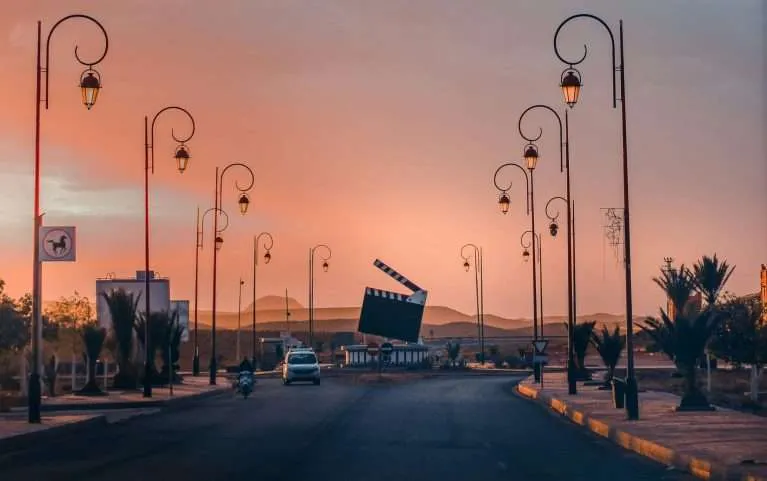 Sunset road through film city Ouarzazate with street lamps and desert light
