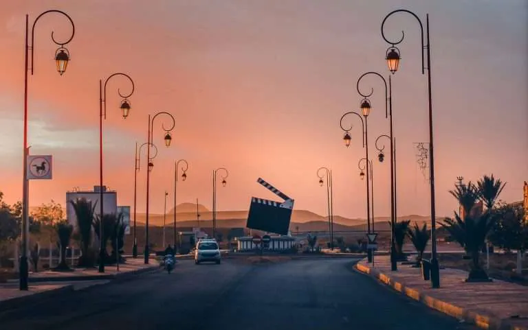 Sunset road through film city Ouarzazate with street lamps and desert light