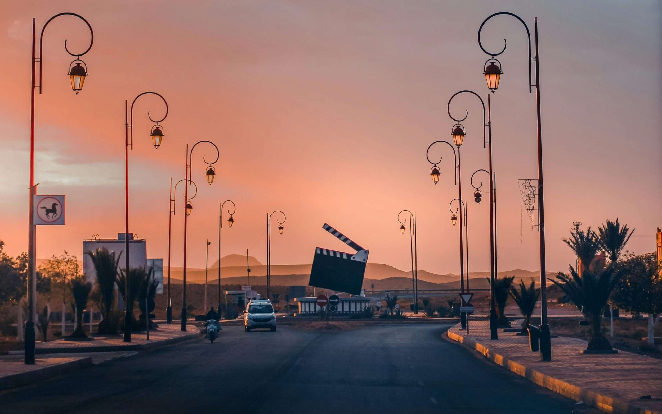 Sunset road through film city Ouarzazate with street lamps and desert light